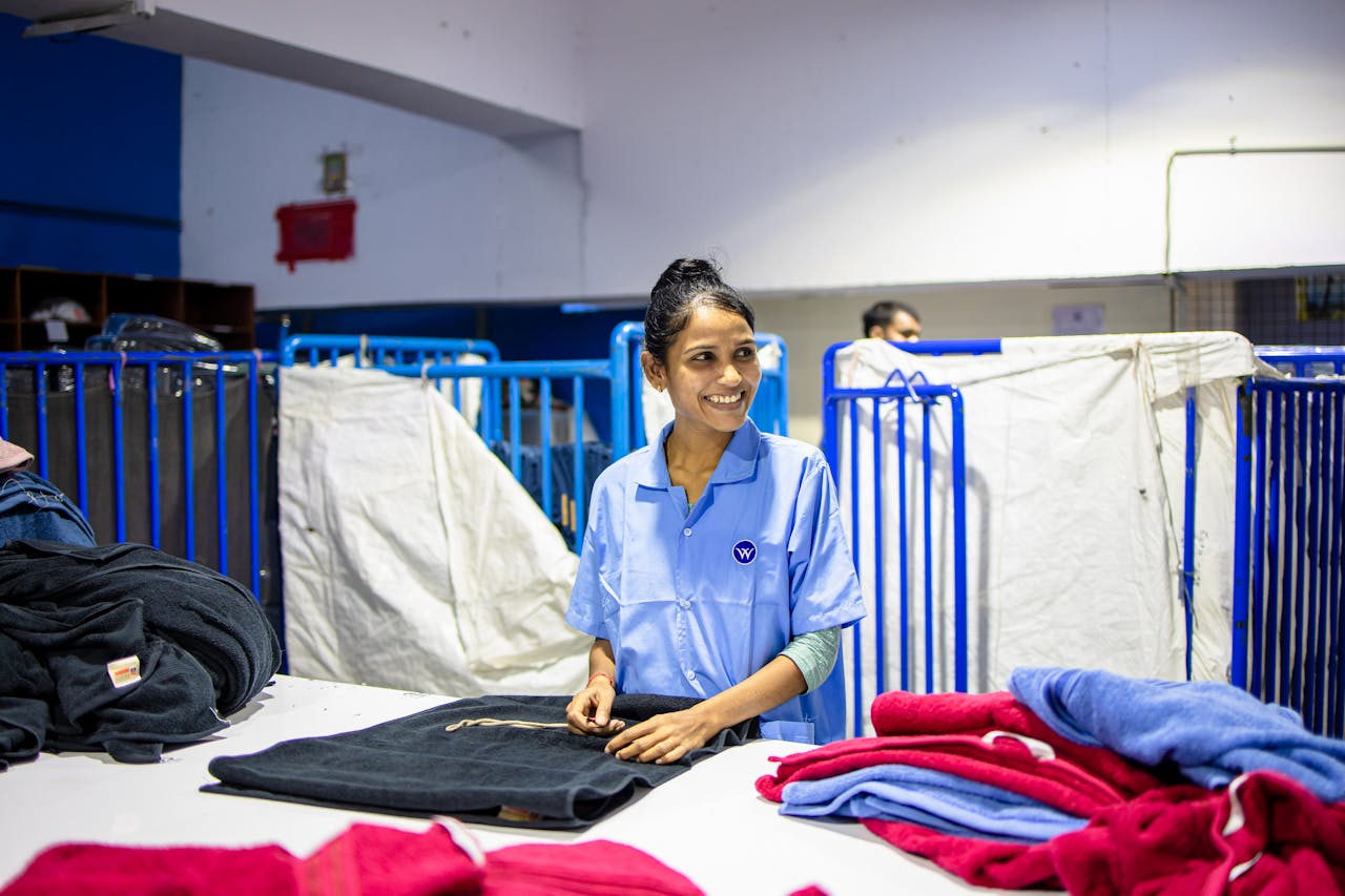 Female textile worker smiling while organizing clothes in a factory.